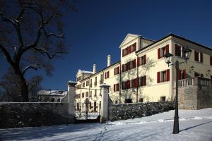 Un grand bâtiment blanc avec des fenêtres rouges dans la neige dans l'établissement Park Hotel Villa Carpenada, à Belluno