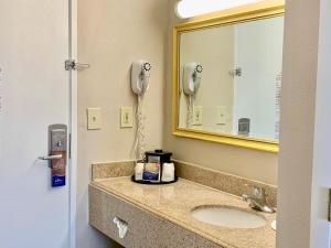 a bathroom with a sink with a mirror and a phone at Baymont by Wyndham Texarkana in Texarkana