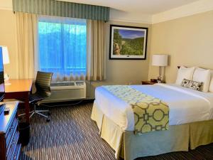 a hotel room with a bed and a desk and a window at Baymont by Wyndham Texarkana in Texarkana