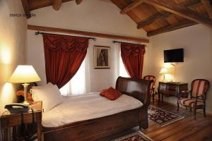 Cette chambre comprend un lit avec des rideaux rouges et un bureau. dans l'établissement Park Hotel Villa Carpenada, à Belluno