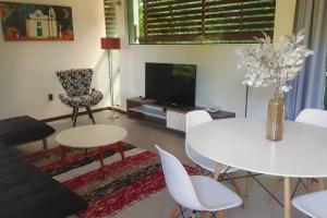 een woonkamer met een witte tafel en een tv bij Casa Pimenta - Apto aconchegante perto da rua do Mucugê in Porto Seguro