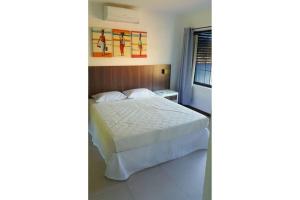 a bedroom with a white bed and a window at Casa Pimenta - Apto aconchegante perto da rua do Mucugê in Porto Seguro