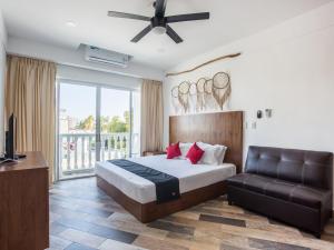 a bedroom with a bed and a couch and a television at Capital O Cancun Ocean View, Cancún in Cancún