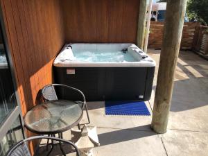 a hot tub sitting on a patio with a chair at Seasidestyle in Raglan