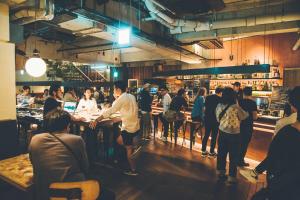 a group of people standing around a bar in a restaurant at CITAN Hostel in Tokyo +43 photos