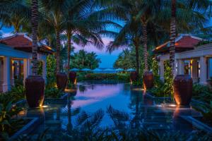 a resort pool with palm trees at night at The Anam Cam Ranh in Cam Ranh