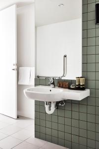 a white sink in a bathroom with green tiles at Lanbruk Richmond Hill in Melbourne