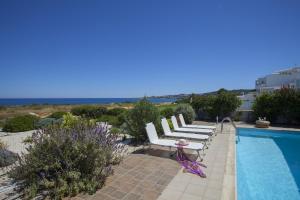 un grupo de sillas blancas sentadas junto a una piscina en Protaras Seafront Villa Melissa, en Protaras