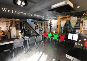 un restaurante con sillas rojas y verdes y una barra en Gudeok Guesthouse en Seogwipo