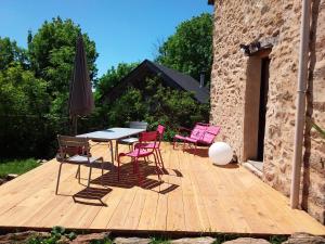 eine Holzterrasse mit einem Tisch, Stühlen und einem Sonnenschirm in der Unterkunft Chambre d'hôtes en Segala in La Salvetat-Peyralès