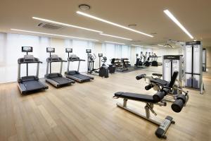 a gym with several treadmills and machines in a room at Shilla Stay Jeju in Jeju