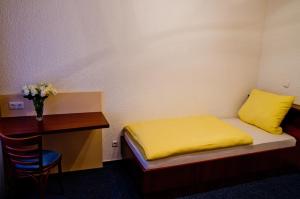 ein kleines Schlafzimmer mit einem gelben Bett und einem Schreibtisch in der Unterkunft Hotel Stella in Netphen