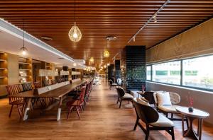 un ristorante con soffitti in legno, tavoli e sedie di Xence hotel Xiamen a Xiamen