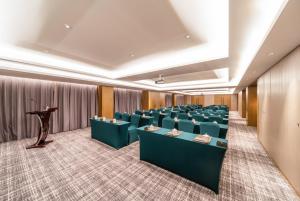 una sala conferenze con sedie verdi e un podio di Xence hotel Xiamen a Xiamen