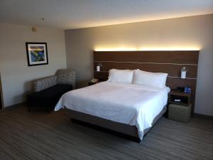 a hotel room with a large bed and a chair at Holiday Inn Express Stephens City by IHG in Stephens City