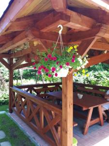 a wooden pergola with a table and flowers at Chata z bali in Sucha Beskidzka
