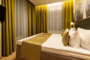 a bedroom with a large bed with yellow curtains at Centennial Nexus Hotel Tallinn in Tallinn