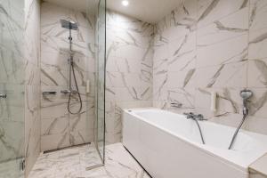 a bathroom with a shower and a tub and a sink at Centennial Nexus Hotel Tallinn in Tallinn