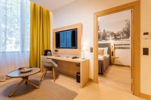 a hotel room with a desk and a bedroom at Centennial Nexus Hotel Tallinn in Tallinn
