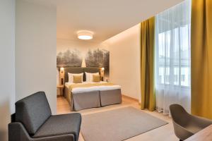 a bedroom with a bed and a chair at Centennial Nexus Hotel Tallinn in Tallinn
