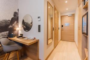 a room with a desk and a hallway with a door at Centennial Nexus Hotel Tallinn in Tallinn