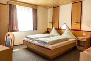 a hotel room with a bed with pillows on it at Gäste- und Appartementhaus Roswitha Huber in Würding