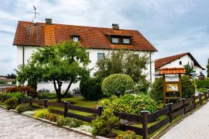 a house with a fence in front of a garden at Gäste- und Appartementhaus Roswitha Huber in Würding