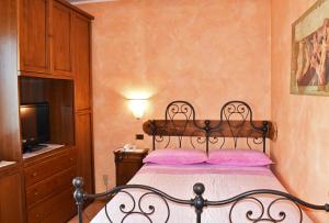 a bedroom with a bed with pink pillows and a television at Albergo Ristorante Conca Azzurra in Colico