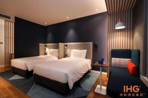 Holiday Inn Express Litang, an IHG Hotel في Lithang: غرفة نوم بسريرين وكرسي فيها
