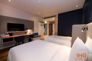 um quarto de hotel com duas camas e uma secretária com uma televisão em Holiday Inn Express Litang, an IHG Hotel em Lithang