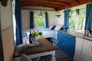 a room with a table and a bed with blue curtains at B&B Welgelegen in Workum