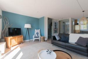 a living room with a black couch and a tv at Vakantiehuis aan het Veerse Meer in Kortgene