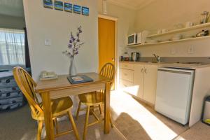 uma cozinha com uma mesa e cadeiras e um frigorífico em Arrow Motel Apartments em Nelson