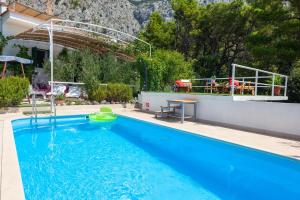 a large blue swimming pool with a table and mountains in the background at Villa Ana in Makarska