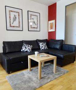 a living room with a black leather couch and a coffee table at Les Millepertuis in Les Ulis