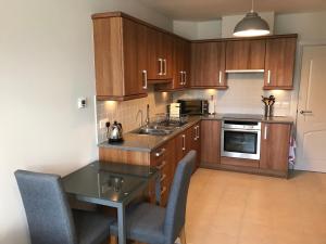 a kitchen with wooden cabinets and a table and chairs at 3 Argyle Place in Dornoch