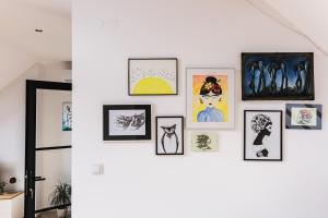 a wall of framed pictures on a white wall at Apartament Dobre Miejsce 2 in Ustrzyki Dolne