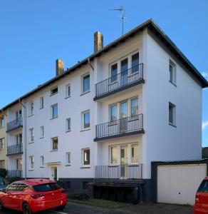 un edificio blanco con un coche rojo aparcado delante en Apartmenthaus in der Metzstraße, en Bochum