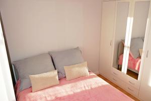 łóżko z 2 poduszkami i lustrem w pokoju w obiekcie Apartament 15 w Świnoujściu
