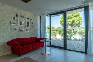 a living room with a red couch and a glass door at Hotel Sveti Kriz in Trogir
