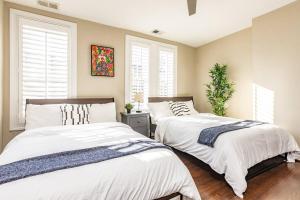 two beds in a bedroom with two windows at Astonishing Old Town Colonial Home with parking CozySuites in Alexandria