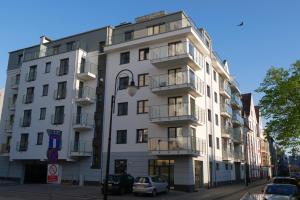 biały budynek z zaparkowanymi przed nim samochodami w obiekcie Apartament 15 w Świnoujściu