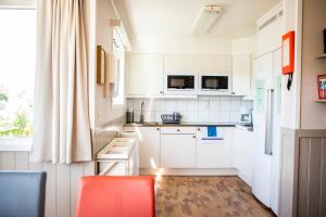 a kitchen with white cabinets and a red chair at Lisebergsbyns Vandrarhem in Gothenburg