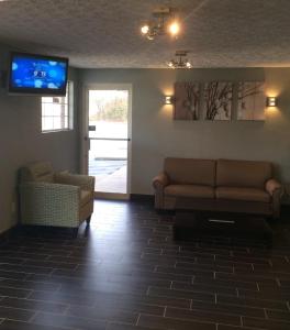 a living room with a couch and a tv on the wall at Boarders Inn & Suites by Cobblestone Hotels - Ashland City in Ashland City