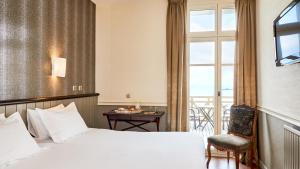 a hotel room with a bed and a table and a window at Hôtel Le Beaufort in Saint Malo