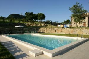 una piscina con mesa y sillas junto a ella en Appartamento Melograno in casale con piscina - Val d'Orcia, en Radicofani