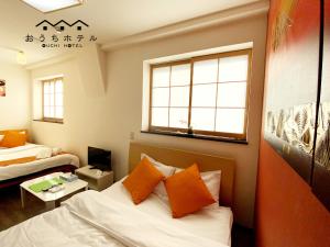 a room with a bed with orange pillows at OUCHI HOTEL Yokogawa in Hiroshima