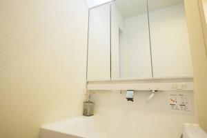 W białej łazience znajduje się umywalka i lustro. w obiekcie アンドステイ高砂2丁目 w Tokio