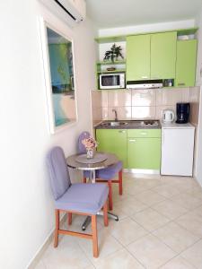 a kitchen with green cabinets and a table and chairs at Apartments Green & Orange in Hvar