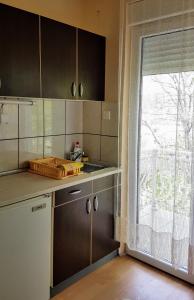 a kitchen with brown cabinets and a large window at Apartmani Smiljanic app 3 in Soko Banja